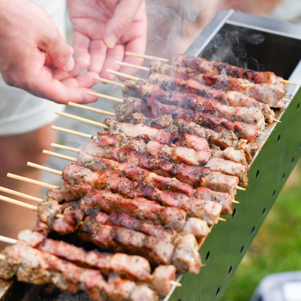 A row of beef skewers being grilled on a barbeque