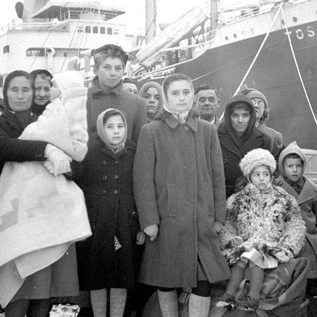 Black and white image of Italian immigrants seen standing in front of a ship