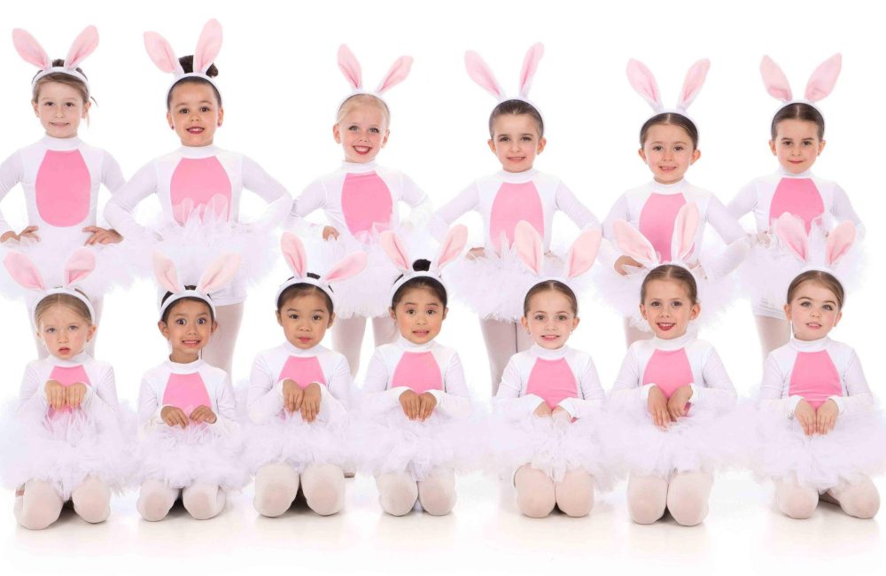 A group of young DanzArts Toronto dance students wearing bunny costumes posing in two rows for a photo.