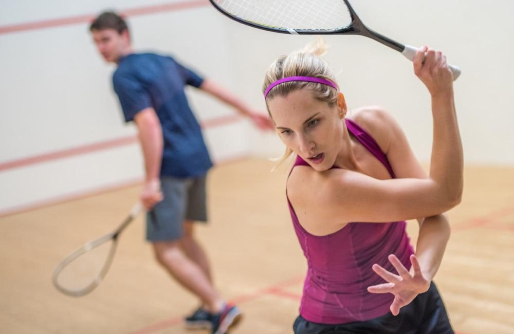 Two people playing squash in a court.